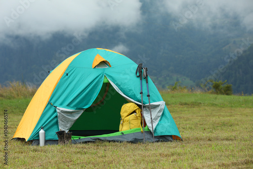 Camping tent and tourist stuff on green grass in mountains