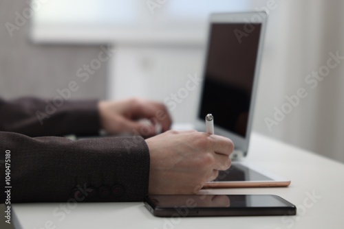 Businessman using different devices at white table indoors, closeup. Modern technology