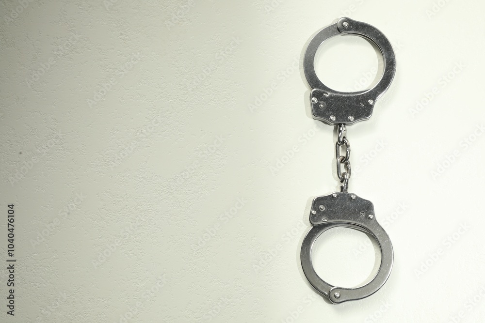 Classic chain handcuffs on white table, top view. Space for text