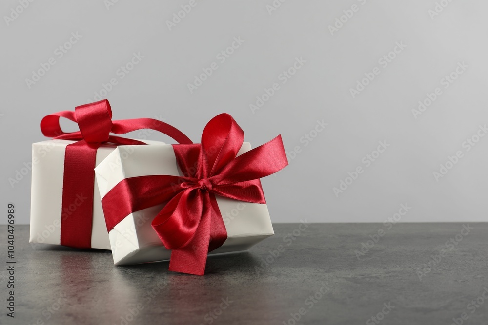 Gift boxes with bows on grey table, space for text Gift boxes with bows on grey table, space for text
