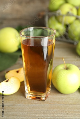 Glass of juice and apples on wooden table