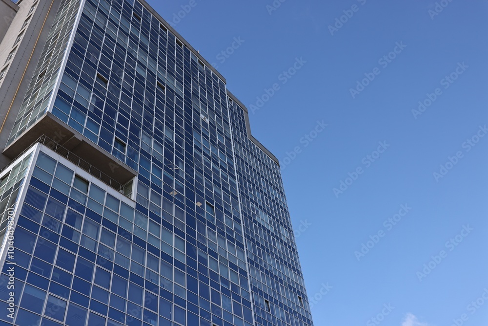 Obraz premium Exterior of modern building with many windows against blue sky, low angle view
