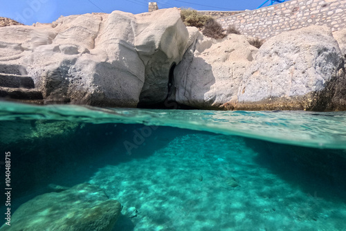 Underwater split photo of small cove and arch rock formations near  famous for colourful boat houses area of Karas, Kimolos island, Cyclades, Greece