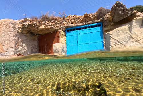 Underwater split photo of small cove and arch rock formations near  famous for colourful boat houses area of Karas, Kimolos island, Cyclades, Greece photo