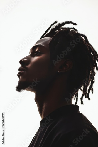 Profile of a young man with dreadlocks against a bright background in a minim...