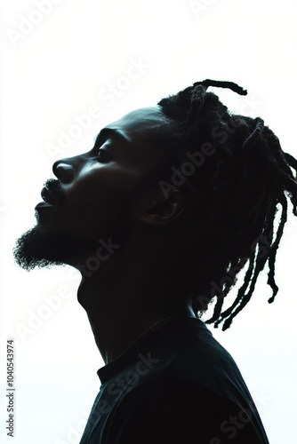 Profile of a young man with dreadlocks against a bright background in a minim...