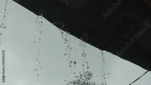 water flowing from the roof. rain drops from the roof of a house