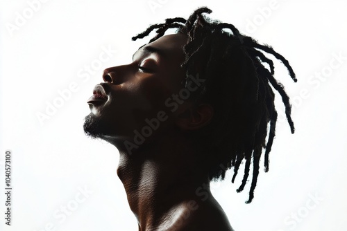 Profile of a young man with dreadlocks gazing upwards against a soft background