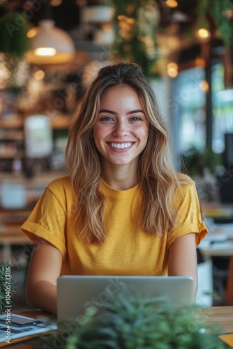 Smiling woman with curly hair working on a laptop in a cozy coffee shop durin...