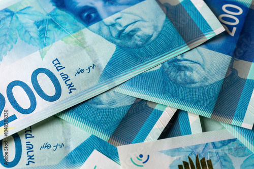 There is a pile of 200 shekel banknotes on the table , a close-up view from above photo