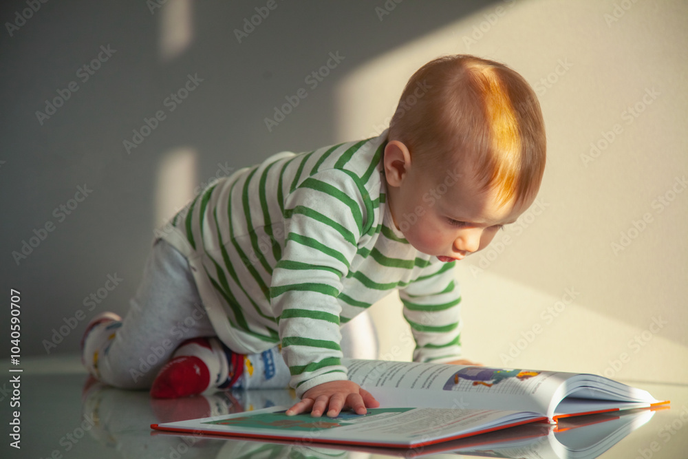 Conceptual image: Development of the baby. Happy little boy reading the book. Horizontal image.