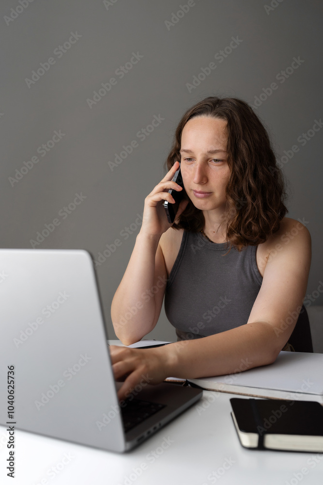 Woman managing work calls while sitting at home with laptop and notebook Woman managing work calls while sitting at home with laptop and notebook