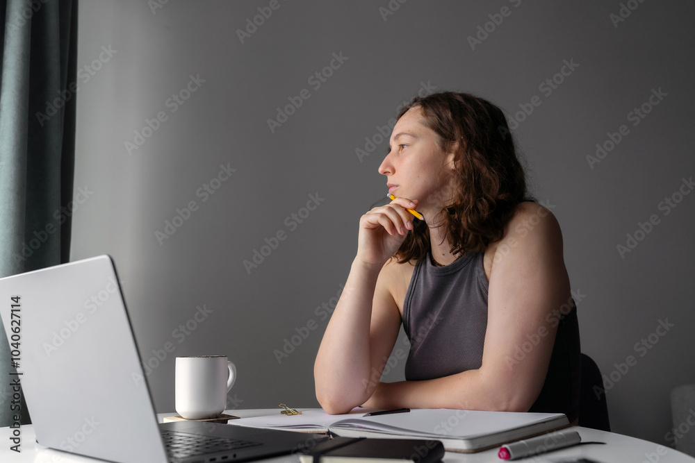 Thoughtful woman at desk working from home with a cup of coffee Thoughtful woman at desk working from home with a cup of coffee
