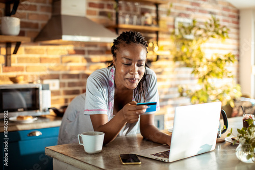 Young woman online shopping in the kitchen at home