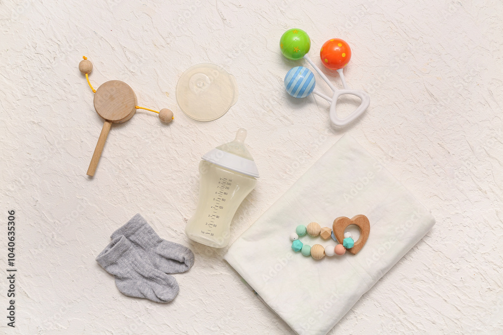 Composition with bottle of milk for baby, toys and accessories on light background Composition with bottle of milk for baby, toys and accessories on light background