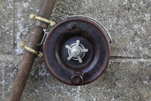 fishing rod reel against a concrete wall