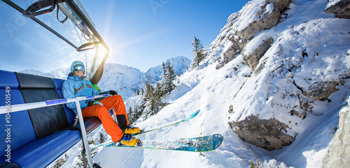 Skier sitting at chairlift on winter mountains during sunny day, Alps, Austria