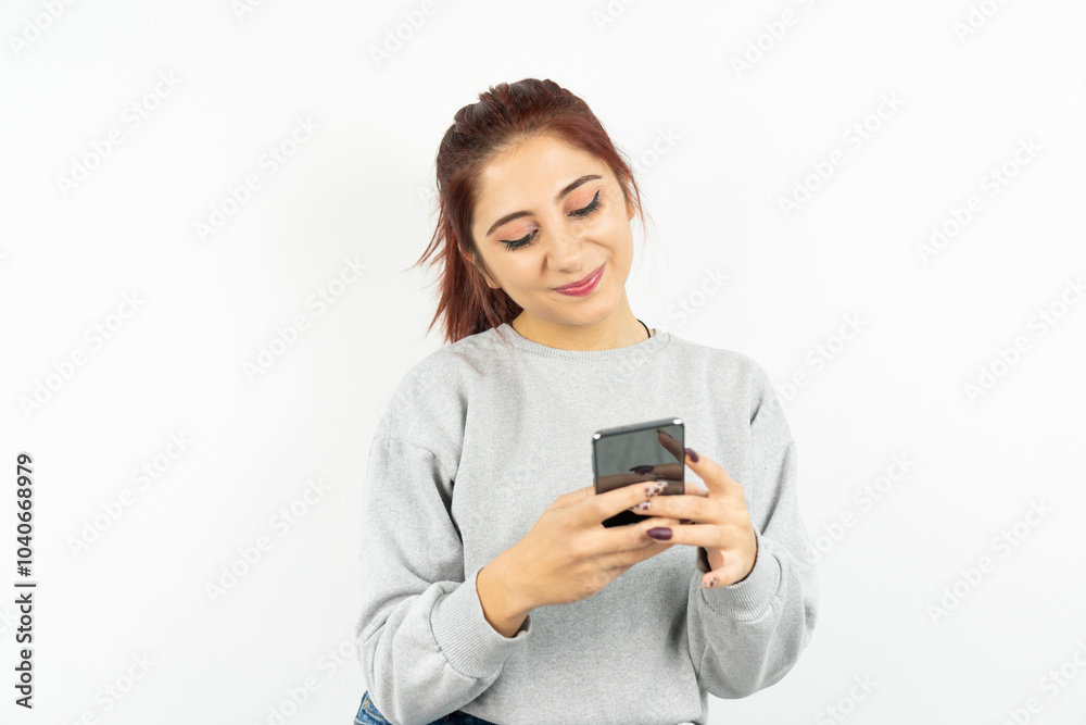 A woman is looking at her cell phone with a smile on her face A woman is looking at her cell phone with a smile on her face