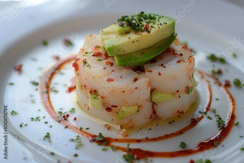 Delicious tuna and avocado starter with spicy sauce is served on white plate