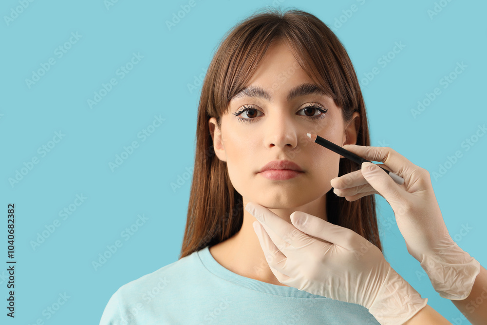 Surgeon hands drawing marks on woman's nose for plastic surgery against blue background Surgeon hands drawing marks on woman's nose for plastic surgery against blue background