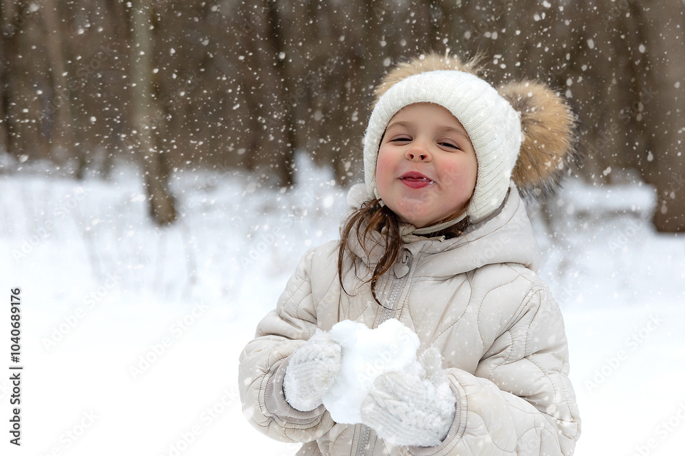 Obraz premium Child girl bite ice cube of snow in park. Little girl eating snow ice outdoors in winter day. Kids cold and flu concept.
