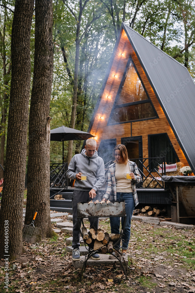 Couple grilling skewers together, enjoying barbecue in forest setting with firewood and nature Couple grilling skewers together, enjoying barbecue in forest setting with firewood and nature