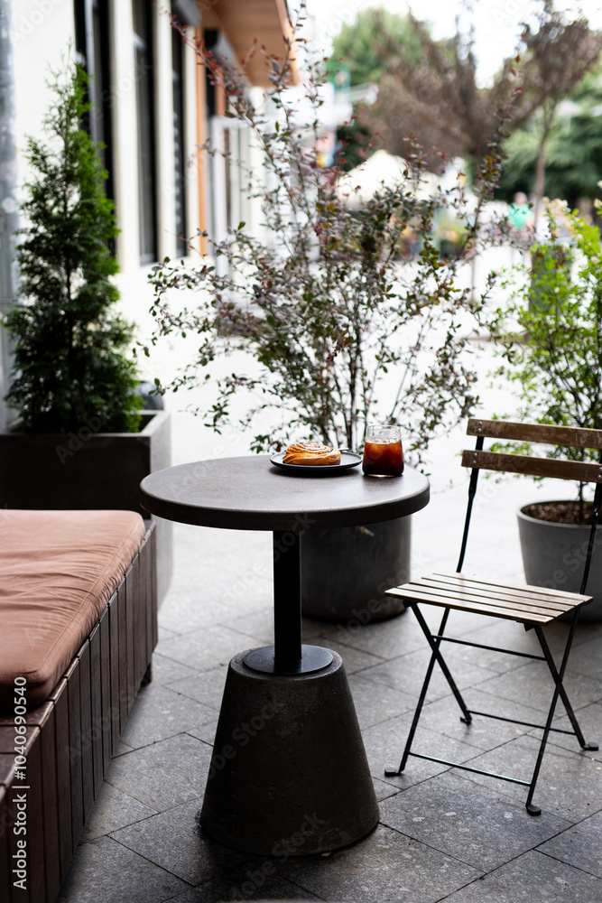 Cozy outdoor café setup with a small round table, a pastry, and a drink on a sunny day in an urban setting Cozy outdoor café setup with a small round table, a pastry, and a drink on a sunny day in an urban setting