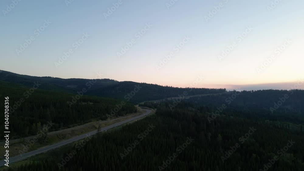 Aerial view of a winding highway through a mountain forest at sunset. Interior British Columbia, Canada. Aerial view of a winding highway through a mountain forest at sunset. Interior British Columbia, Canada.