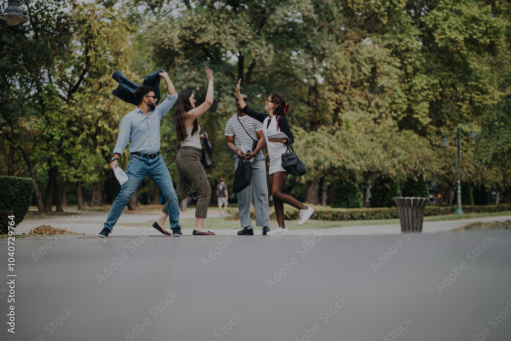 A group of business people shares a joyful moment, high-fiving and laughing in a lush city park, showcasing teamwork and friendship in a casual outdoor setting. A group of business people shares a joyful moment, high-fiving and laughing in a lush city park, showcasing teamwork and friendship in a casual outdoor setting.