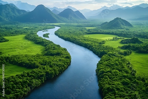 Aerial view of a winding river cutting through lush green landscapes and mountains under a clear blue sky, creating a serene and picturesque natural scene.