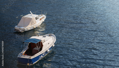 This banner features two small boats floating peacefully on calm, blue waters. The boats are anchored or docked with one of them having a white cover over its cabin, while the other has an open cabin.
