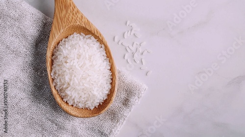 A wooden spoon filled with jasmine rice, placed on a textured linen cloth with natural lighting, highlighting the simplicity and beauty of the grains