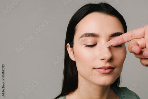 Rhinoplasty. Plastic surgeon is taping nose to patient during rhinoplasty recovery. Applying bandage on nose after surgery to support its shape, decrease swelling and improve appearance.