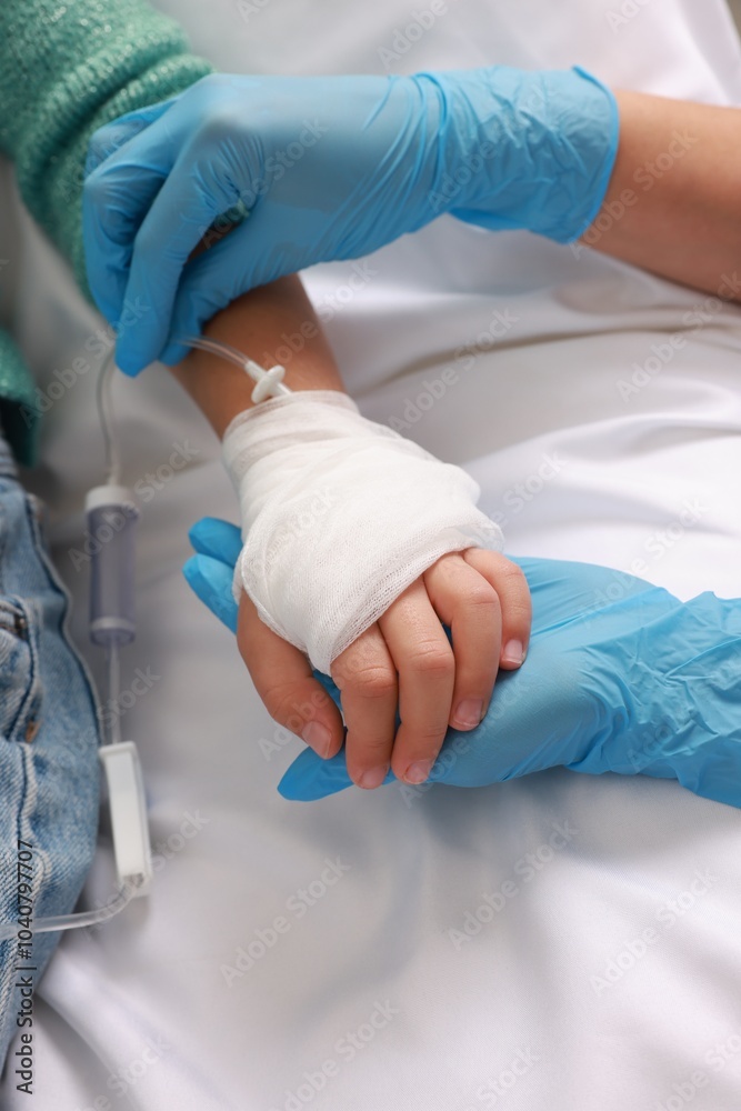 Fototapeta premium Doctor and child with IV drip in hospital, closeup