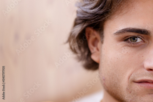 Close-up of young man smiling softly, showing half of his face, copy space, at home photo