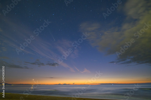 The coastal sunset turns into a starry night. In the sky comet C/2023 A3 (Tsuchinshan ATLAS), stars and clouds, San Vincenzo, Italy photo