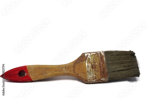 A close-up of a paintbrush. The brush has a wooden handle with a red tip and a worn-out bristle. photo