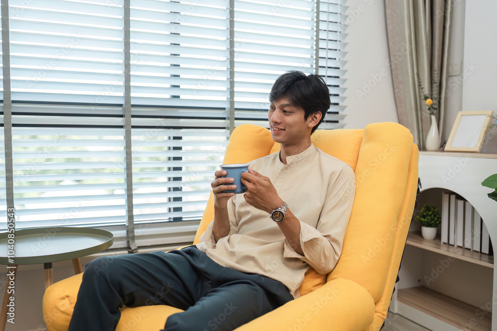 Young Man Relaxing on a Comfortable Yellow Sofa with a Cup of Coffee in a Modern Living Room Young Man Relaxing on a Comfortable Yellow Sofa with a Cup of Coffee in a Modern Living Room