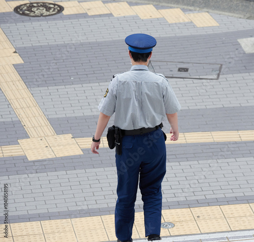 昼の都市の繁華街で巡査している男性警備員の姿 photo