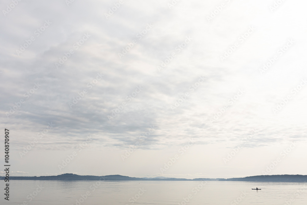 An image of an very early morning kayaker on calm lake waters. An image of an very early morning kayaker on calm lake waters.