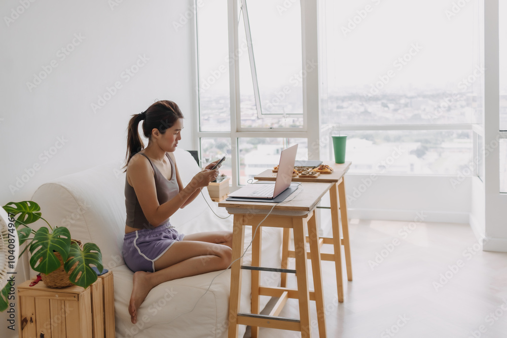Asian woman working at home got distracted with the mobile phone. Asian woman working at home got distracted with the mobile phone.