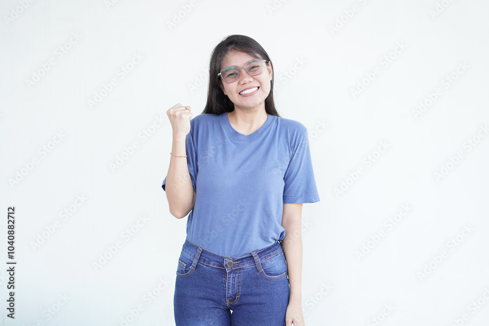 Beautiful Asian woman flashes a bright smile, raising her fists in a triumphant 'yes' victory gesture against a white background Beautiful Asian woman flashes a bright smile, raising her fists in a triumphant 'yes' victory gesture against a white background