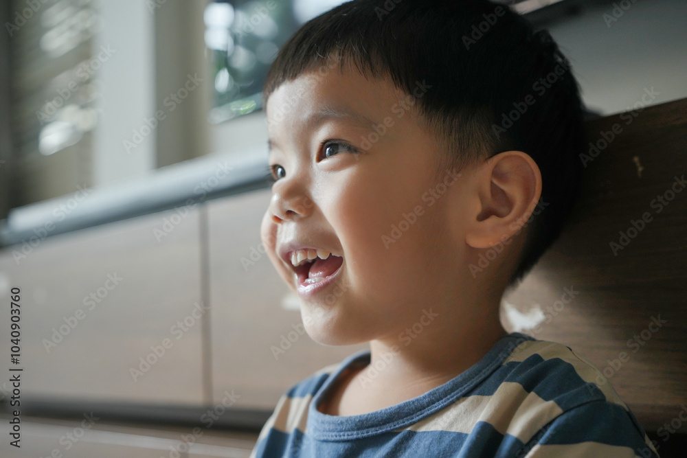 Close-up of a smiling Asian young boy in a striped shirt indoors. Candid portrait photography. Close-up of a smiling Asian young boy in a striped shirt indoors. Candid portrait photography.