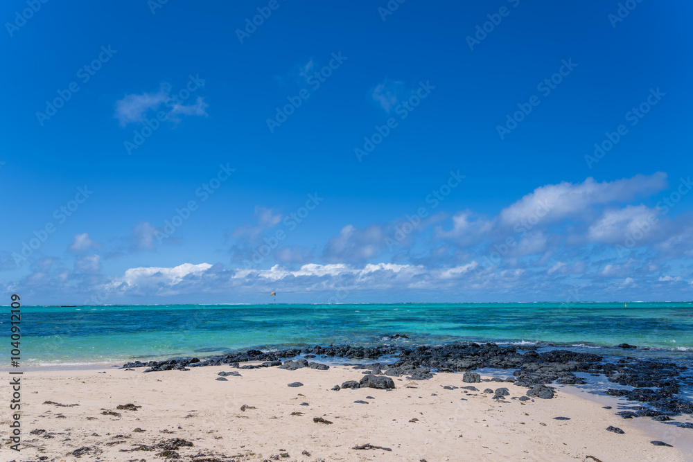 Fototapeta premium Visitors experience the thrill of paragliding in the beautiful lagoon of Ile Aux Cerfs, Mauritius. Visitors can glide effortlessly on the calm waters, surrounded by stunning scenery.