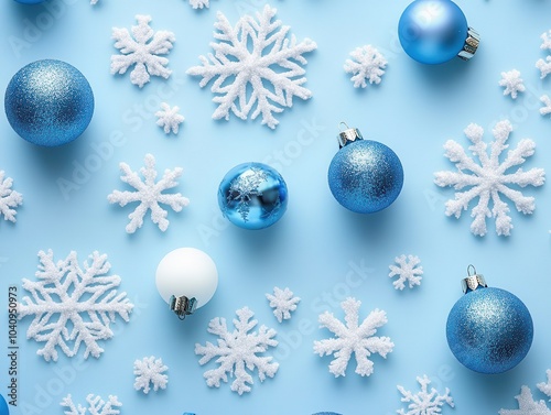 A festive arrangement of blue ornaments and white snowflakes against a soft blue background, evoking a winter holiday theme.