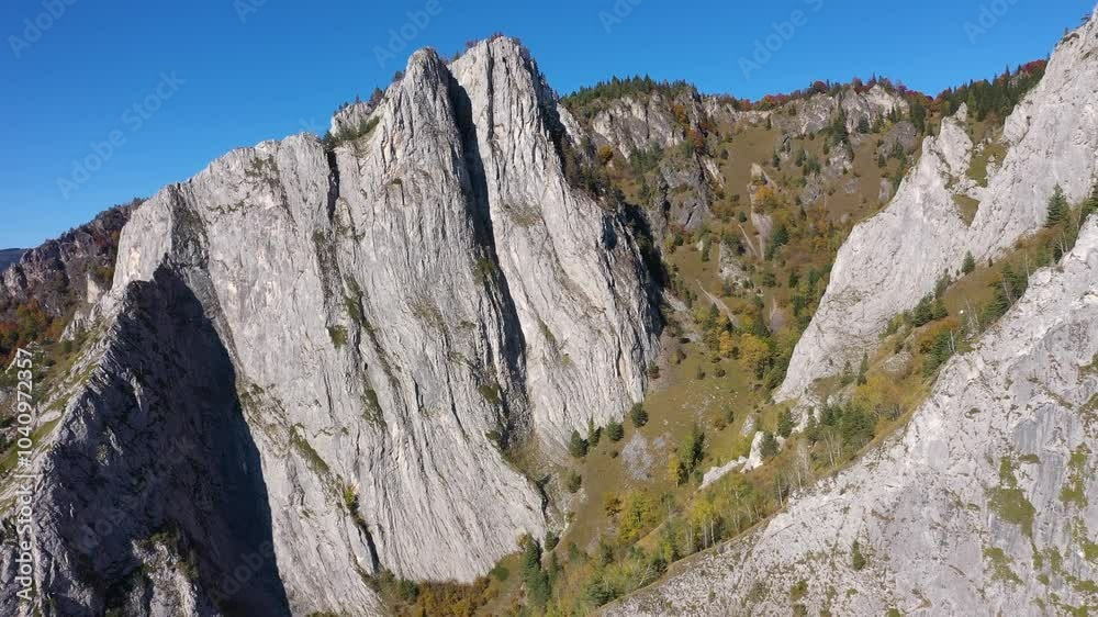 Flying above sunny autumn alpine mountain cliffs and colorful forest by drone Flying above sunny autumn alpine mountain cliffs and colorful forest by drone