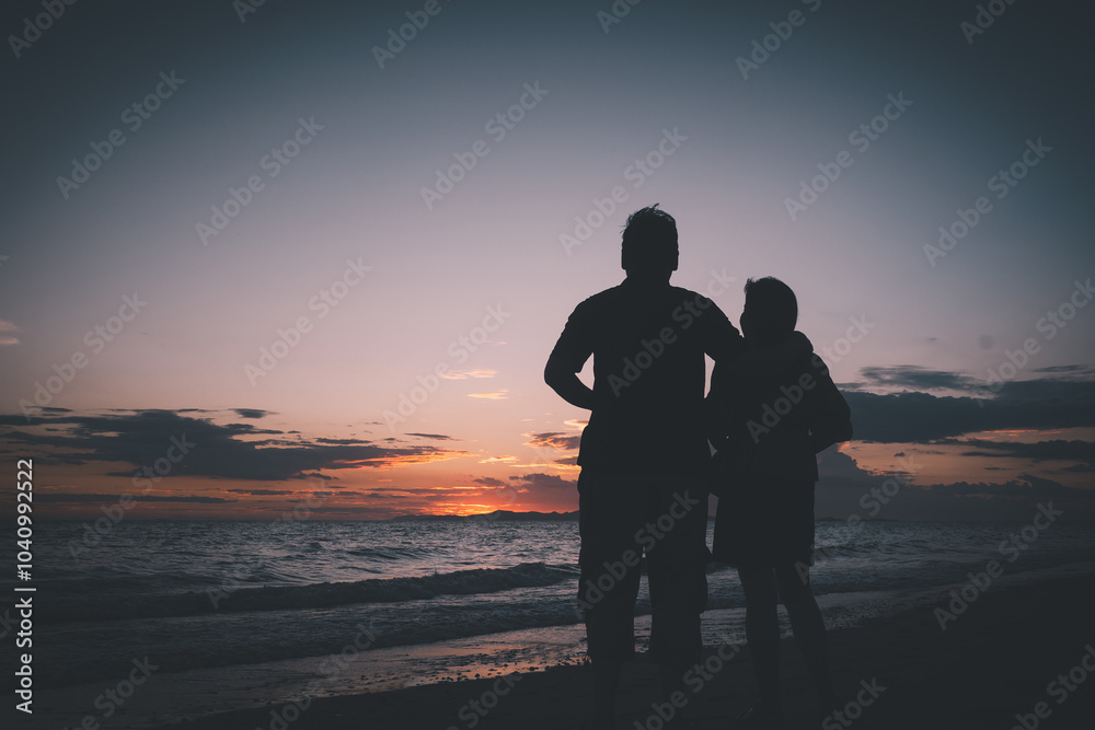 Silhouette of a couple standing on the beach at sunset, embracing and watching the horizon, capturing a peaceful and intimate moment. Silhouette of a couple standing on the beach at sunset, embracing and watching the horizon, capturing a peaceful and intimate moment.