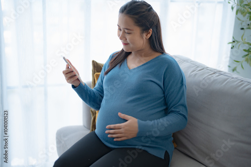 Pregnant asian woman holding smartphone at home using mobile app for pregnant women Positive life moment in pregnancy time Free Download Pregnant asian woman holding smartphone at home using mobile app for pregnant women Positive life moment in pregnancy time - GFXLoad