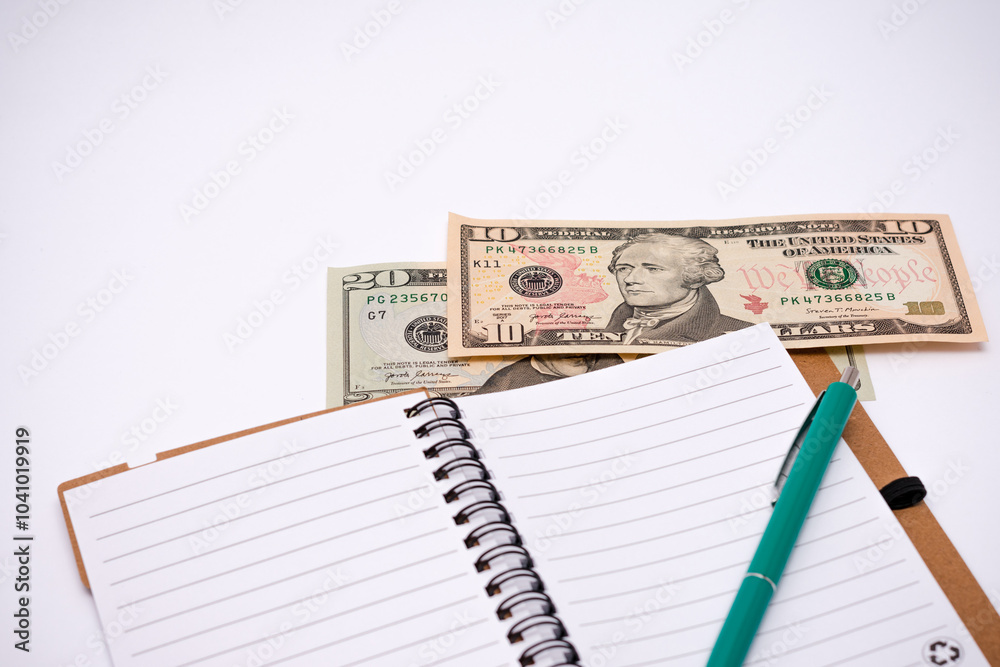 Green pen sits on top of a stack of money in a notebook Green pen sits on top of a stack of money in a notebook