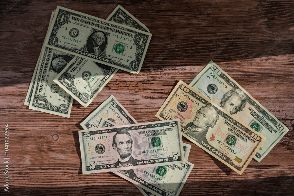A pile of different colored US dollars on a wooden table A pile of different colored US dollars on a wooden table